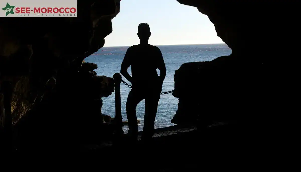 Hercules Cave Tangier tour — visitor silhouette at cave entrance overlooking Atlantic
