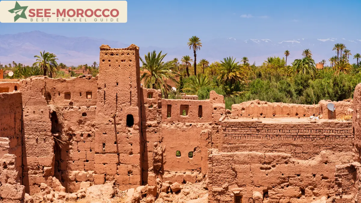 Ruined earthen kasbah among palms with the snow-capped Atlas behind Morocco