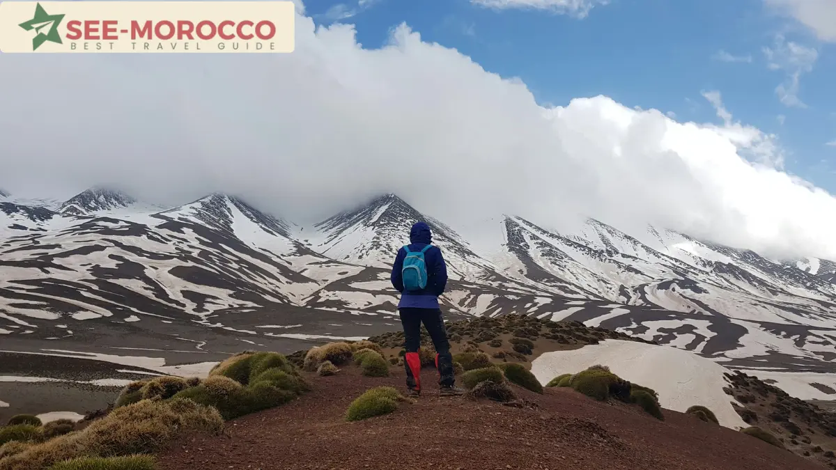Hiker overlooking snow-covered peaks in the Moroccan High Atlas Mountains in winter