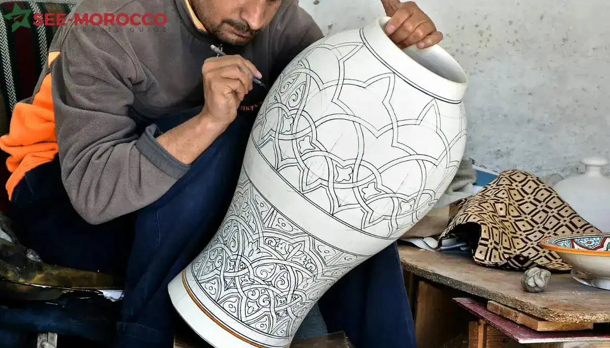 Moroccan handicrafts — artisan hand-drawing geometric patterns on large pottery vase in Fes workshop