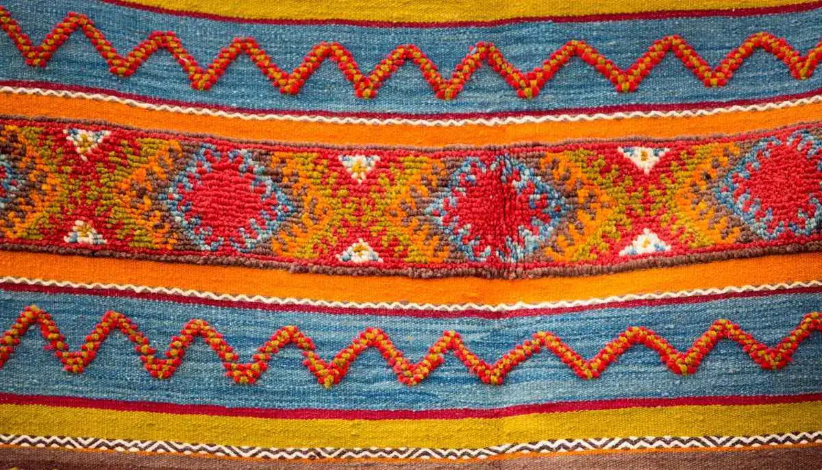 Moroccan rugs — close-up detail of colorful Berber rug with geometric patterns in red orange blue